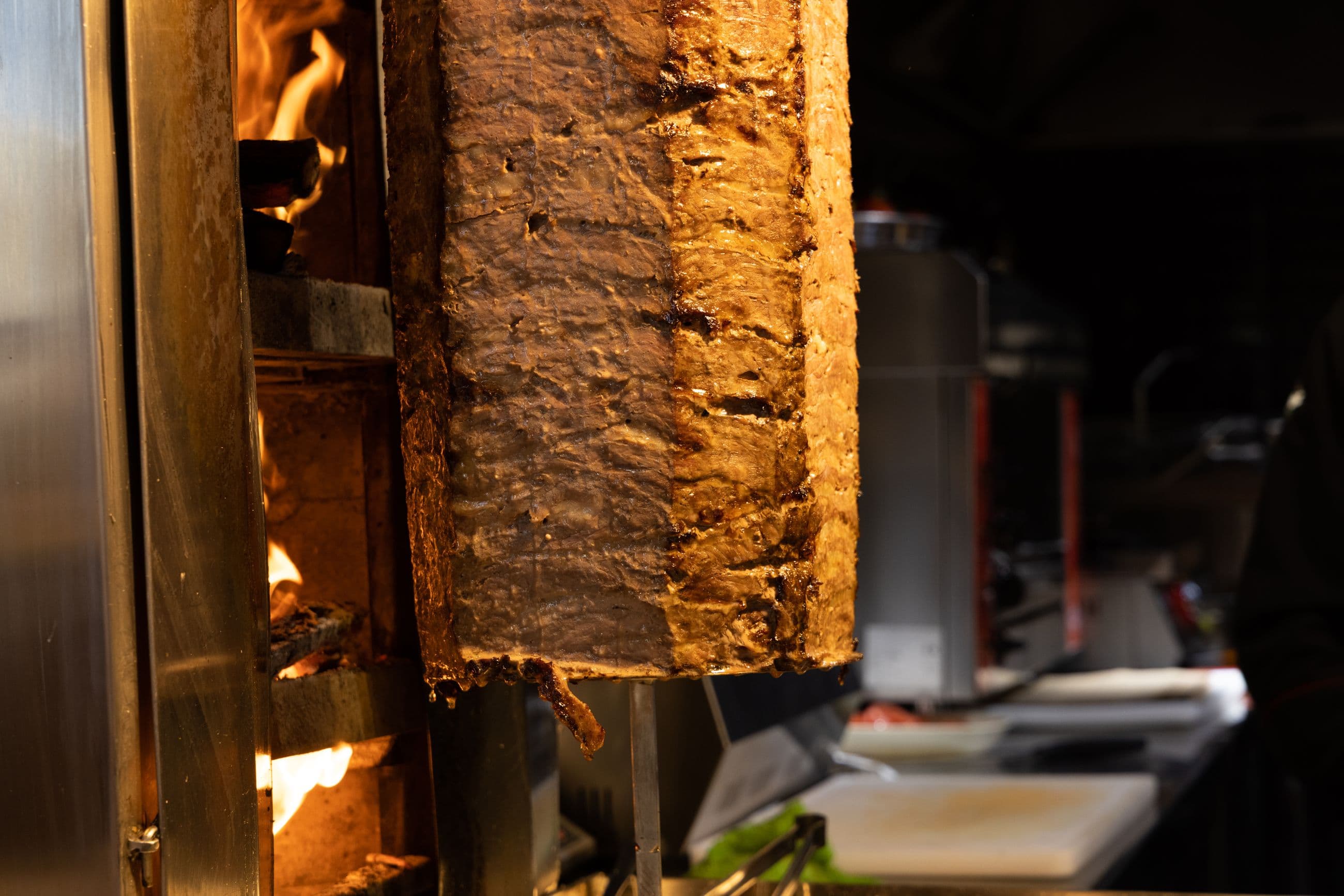 A shawarma spit grilling over an open flame